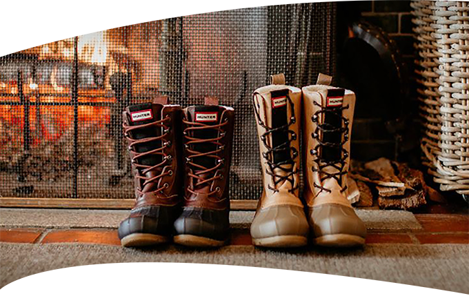 two pairs of winter boots near fireplace